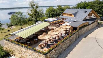 Un restaurante junto al lago con terraza, paredes de piedra y vistas al lago.