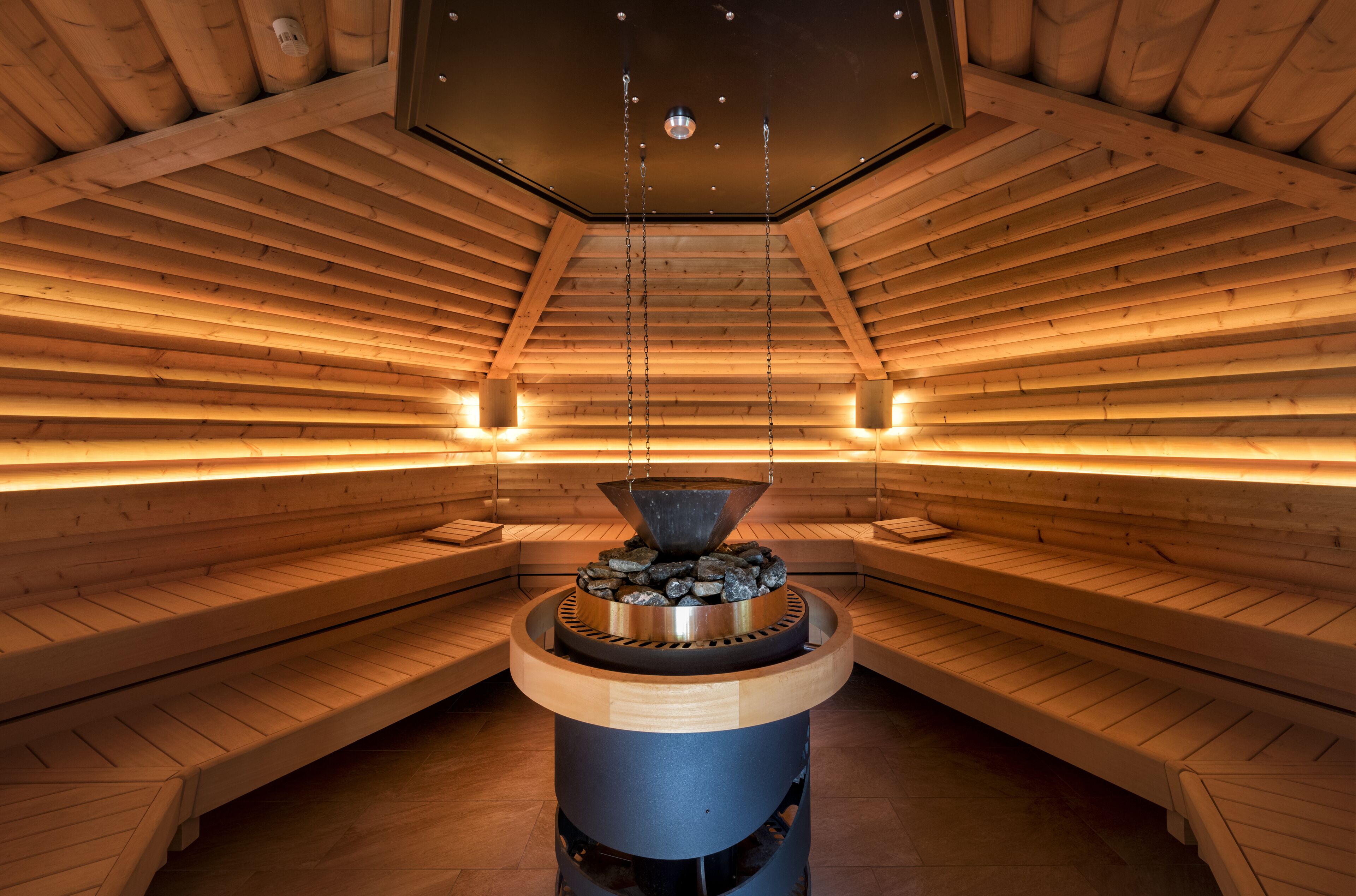 A sauna with wooden benches and a central stone heater.