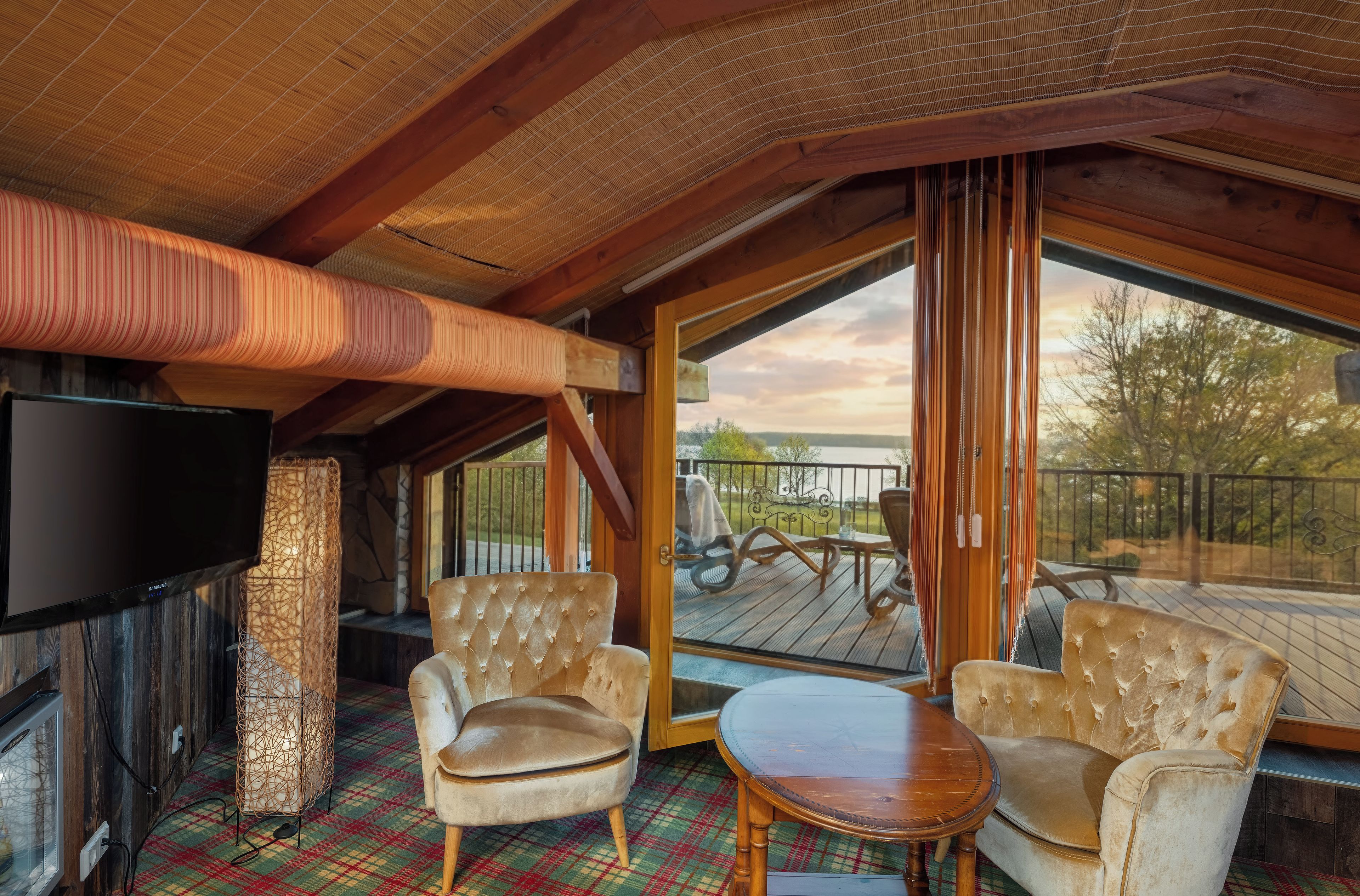 A cozy room with a television, a fireplace, a large window, and a deck with outdoor furniture.