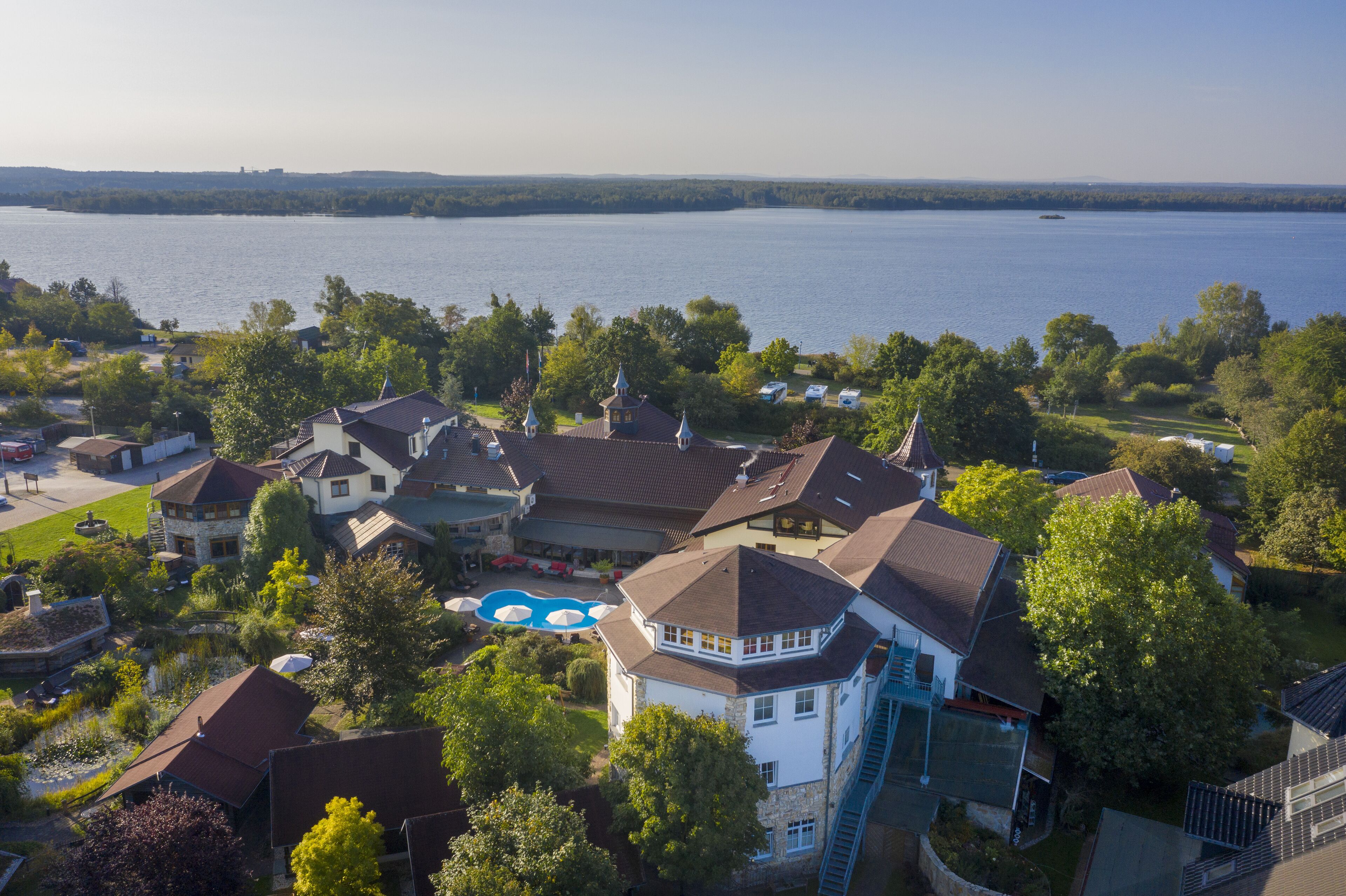 Un quartier résidentiel avec des maisons, une piscine et un lac en arrière-plan.
