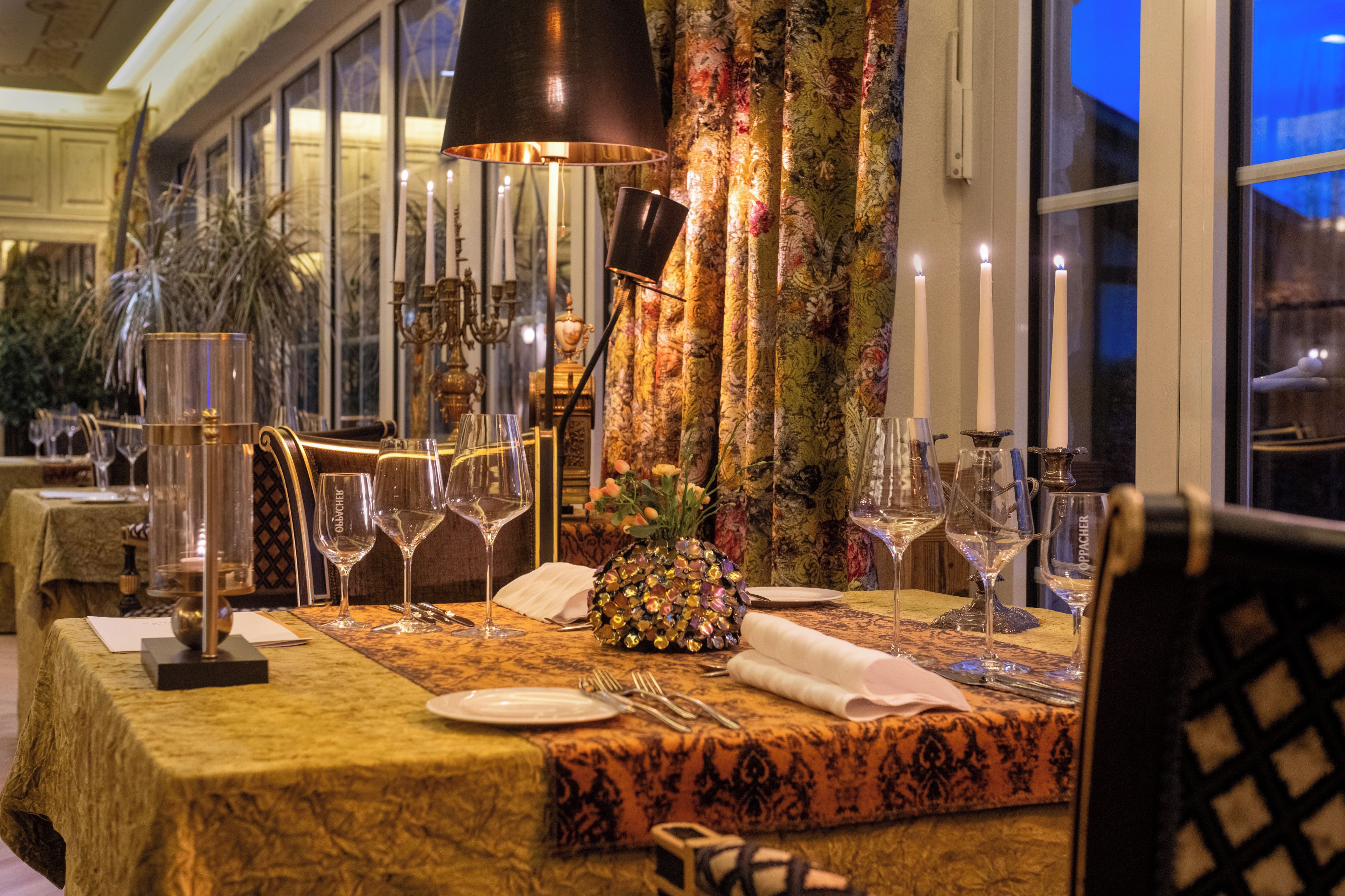 A dining table set for a meal with candles, glasses, and a decorative centerpiece.