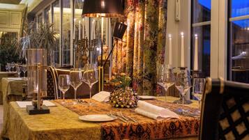 A dining table set for a meal with candles, glasses, and a decorative centerpiece.