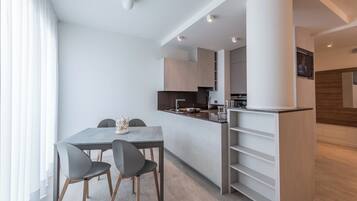 A modern kitchen with a central island, built-in cabinets, and a flat-screen TV mounted on the wall.
