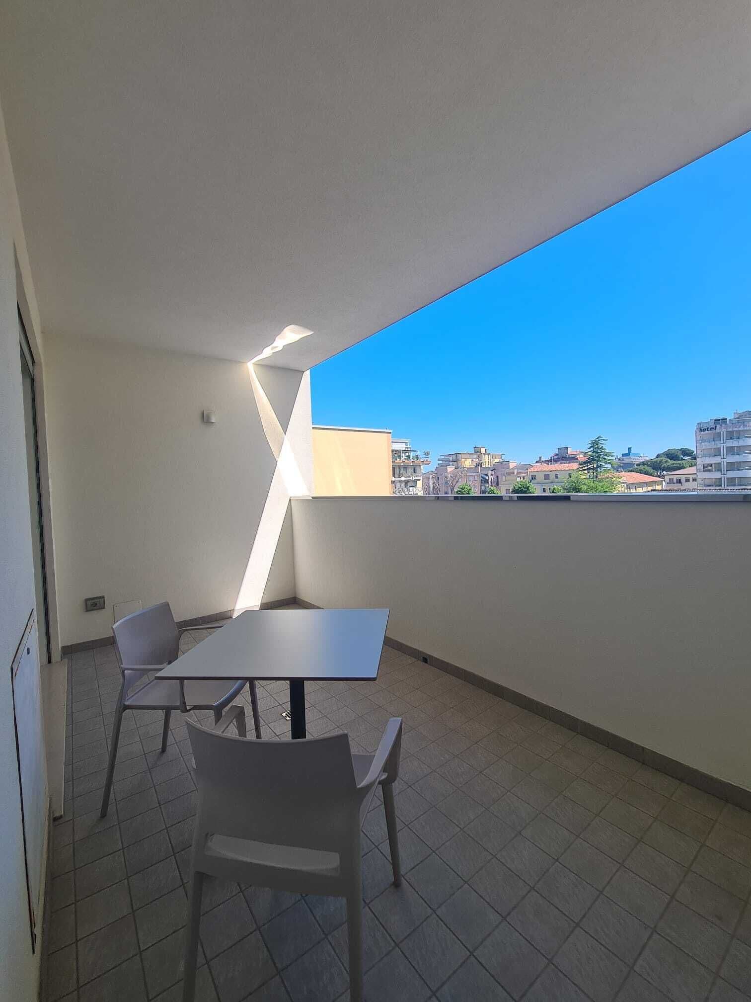 A balcony with a table and chairs, a clear view of the cityscape, and a modern architectural design.