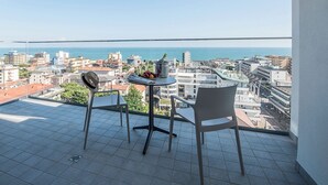 Un balcon avec une table et des chaises, offrant une vue sur le paysage urbain et la mer.