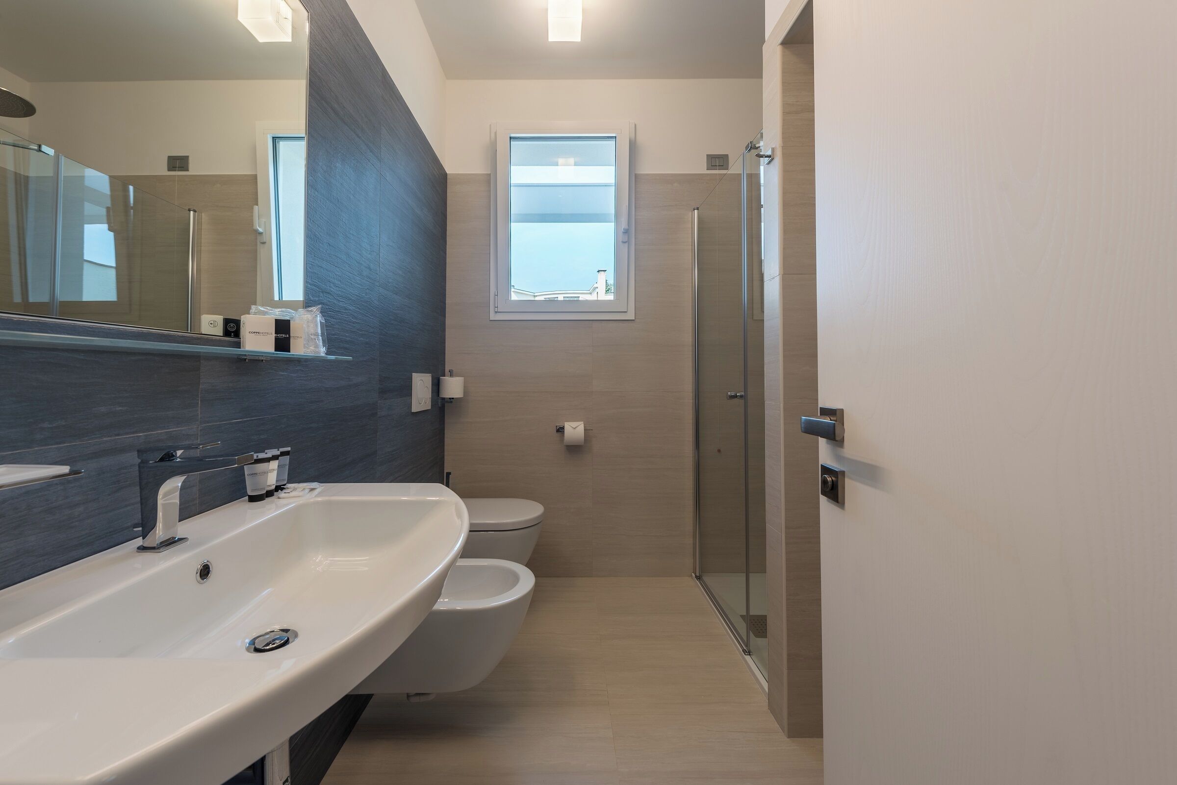 A modern bathroom with a large sink, toilet, and a glass shower enclosure.