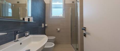 A modern bathroom with a large sink, toilet, and a glass shower enclosure.