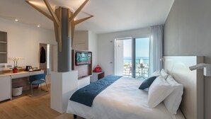 Une chambre d’hôtel moderne avec un grand lit, un bureau et un balcon offrant une vue agréable.