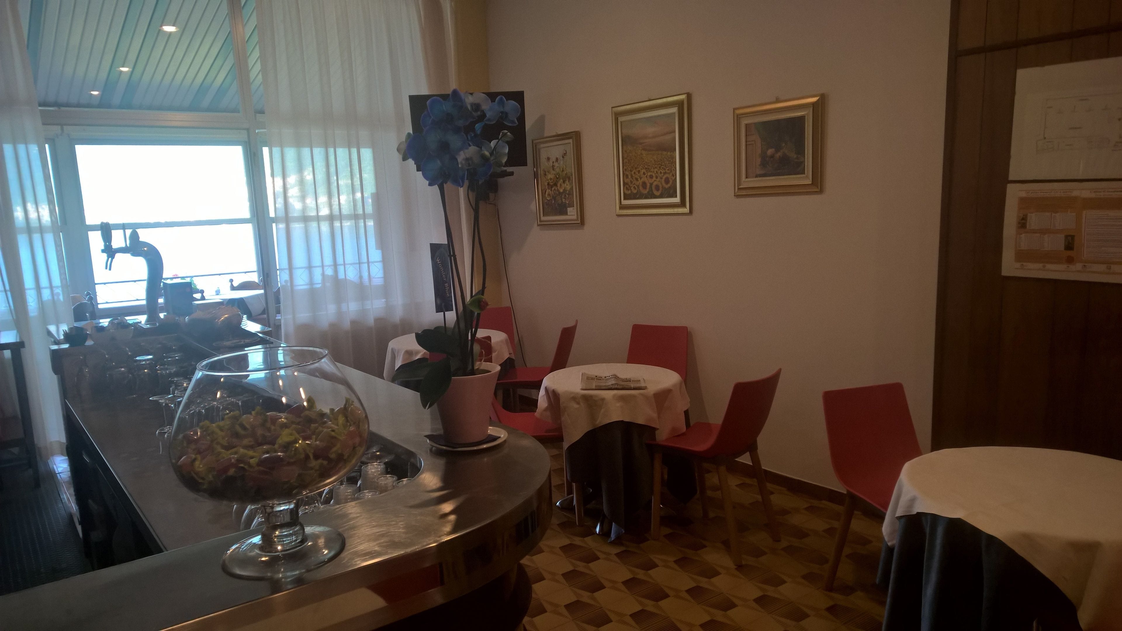 A restaurant interior with a bar area, dining tables, chairs, and framed artwork on the walls.