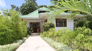 Une maison avec un toit végétalisé, un porche à l’avant et un chemin menant à l’entrée.