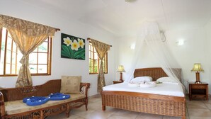 Une chambre à coucher comprenant un lit, un canapé, deux tables de chevet et une fenêtre avec des rideaux.