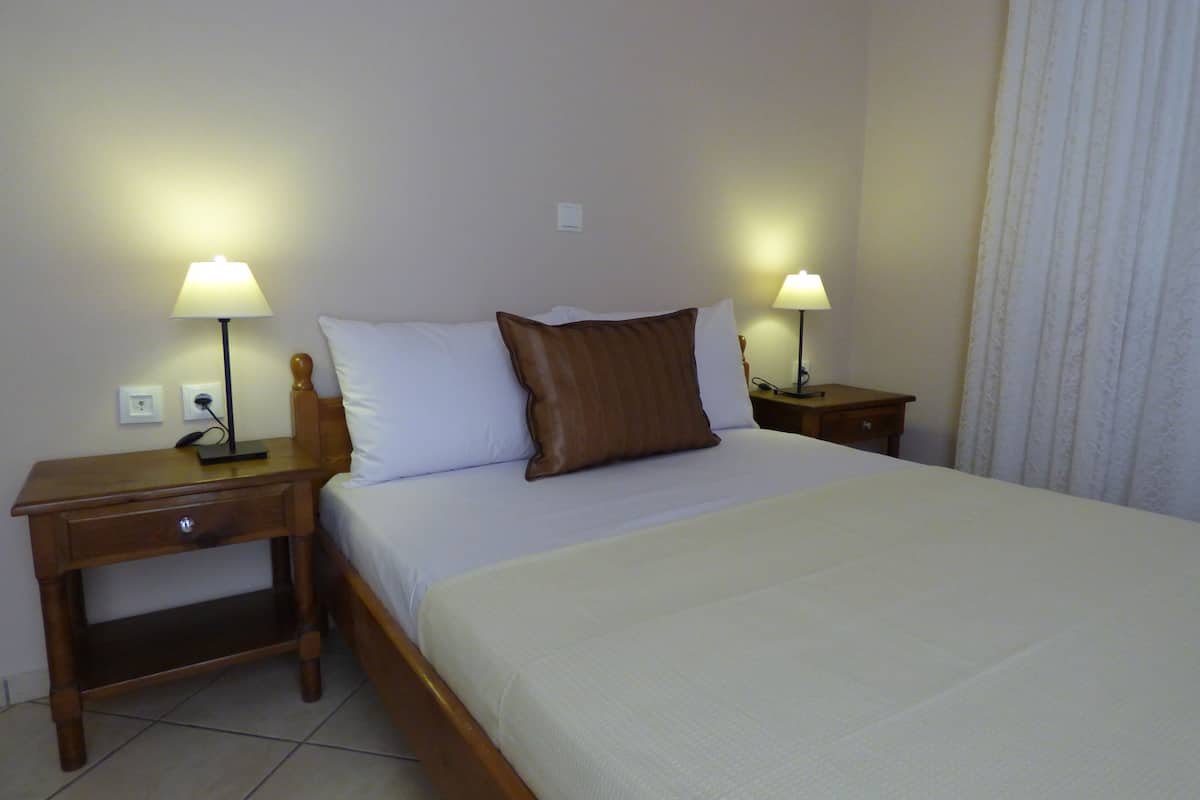 A hotel room with a bed, two bedside tables, and two lamps.