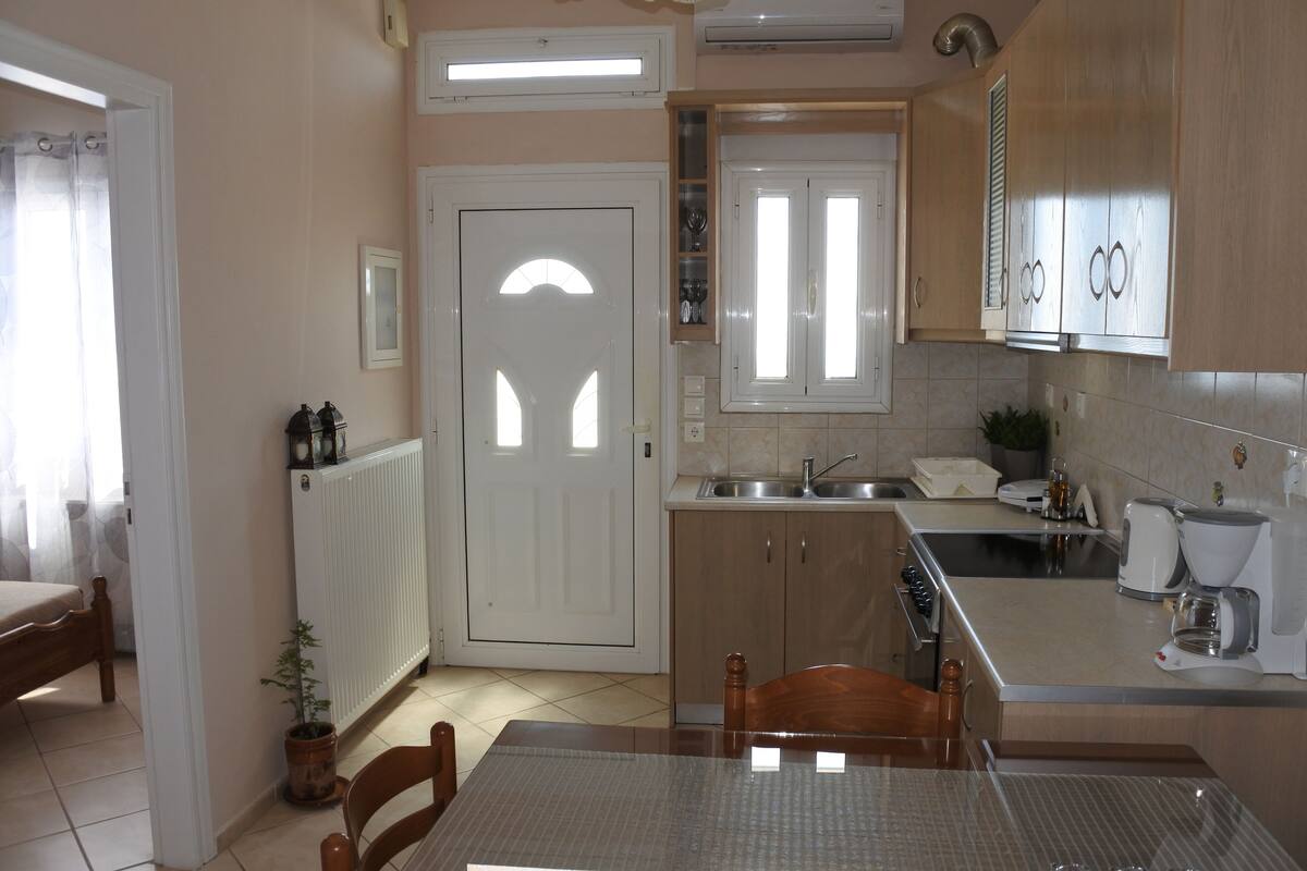 A modern kitchen with a dining area, featuring a central island, built-in cabinets, and a sink.