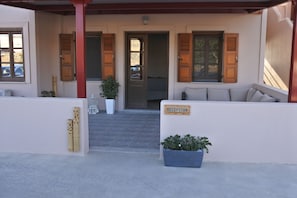 A reception area with a sign, a potted plant, and a bench. - Rampelia apartments (Santorini)