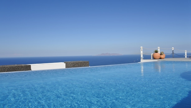 A clear blue sky and a pool with a view of the ocean. - Rampelia apartments (Santorini)