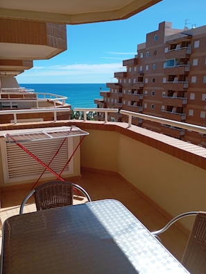 A balcony with a view of the sea, a table, chairs, and a drying rack. - Apartamentos Danesp - Marina D'Or Primera Línea (Oropesa del Mar)