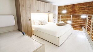 A modern bedroom with a large bed, wooden paneling on the walls, and a white floor.