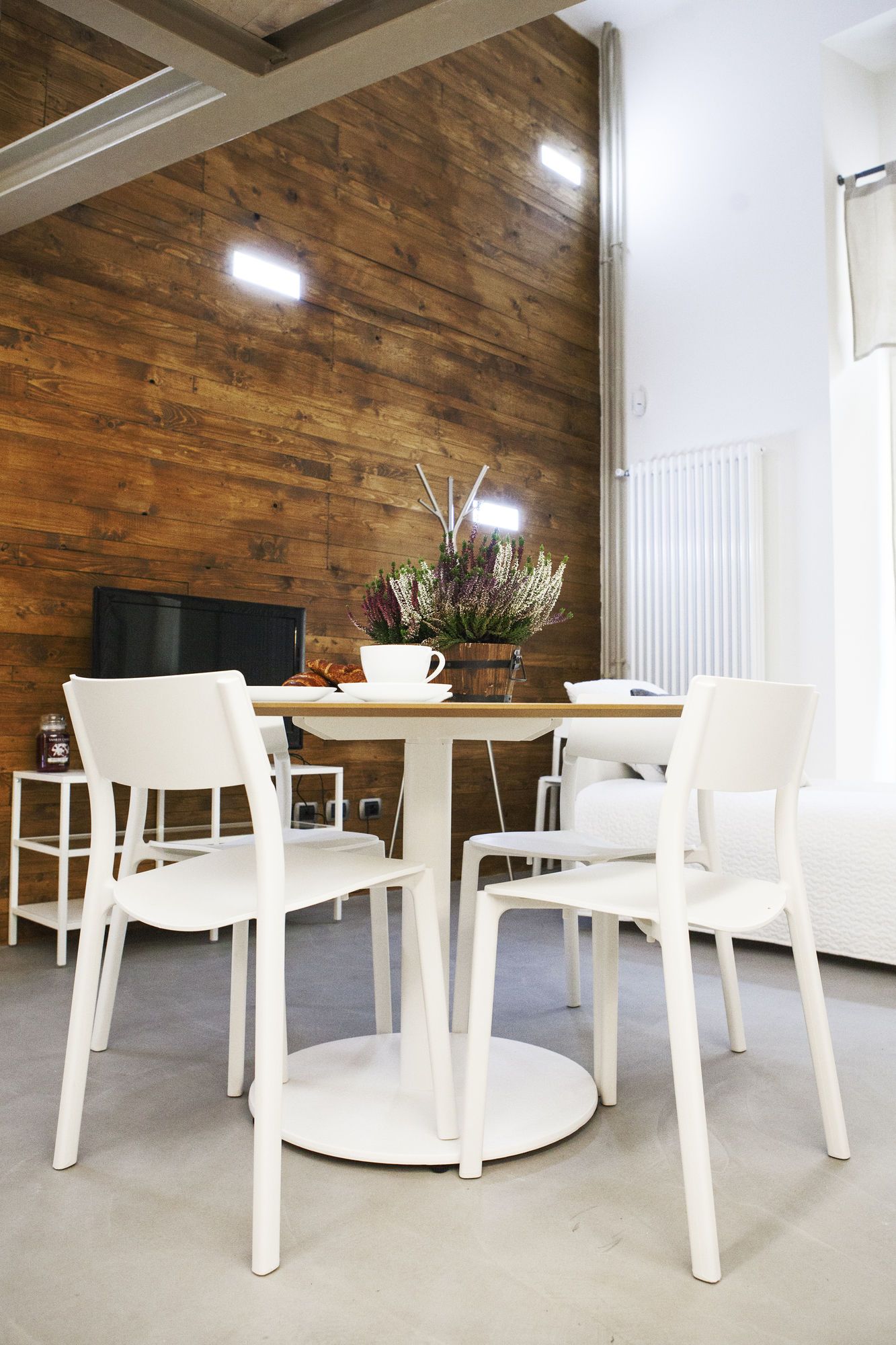 A modern dining area with a round table, white chairs, and a vase of flowers.