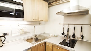 A modern kitchen with wooden cabinets, a stainless steel sink, and a black stove.