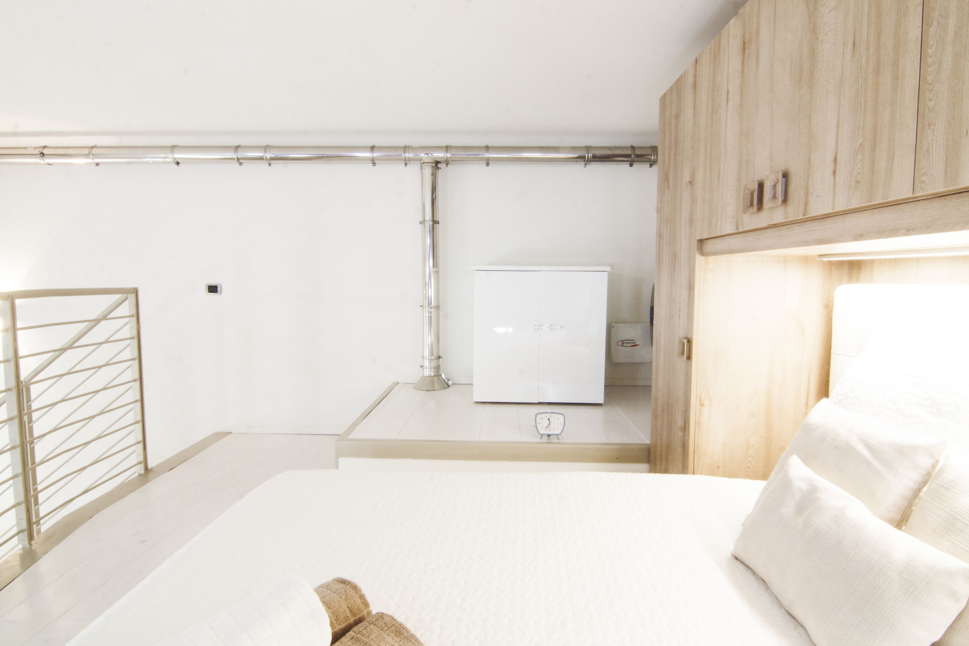 A modern bedroom with a bed, wooden wardrobe, and a white radiator.