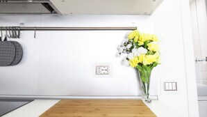 A kitchen with a built-in oven, a wooden cutting board, and a vase with flowers. - Alessia's Flat - Paolo Sarpi (Milan)