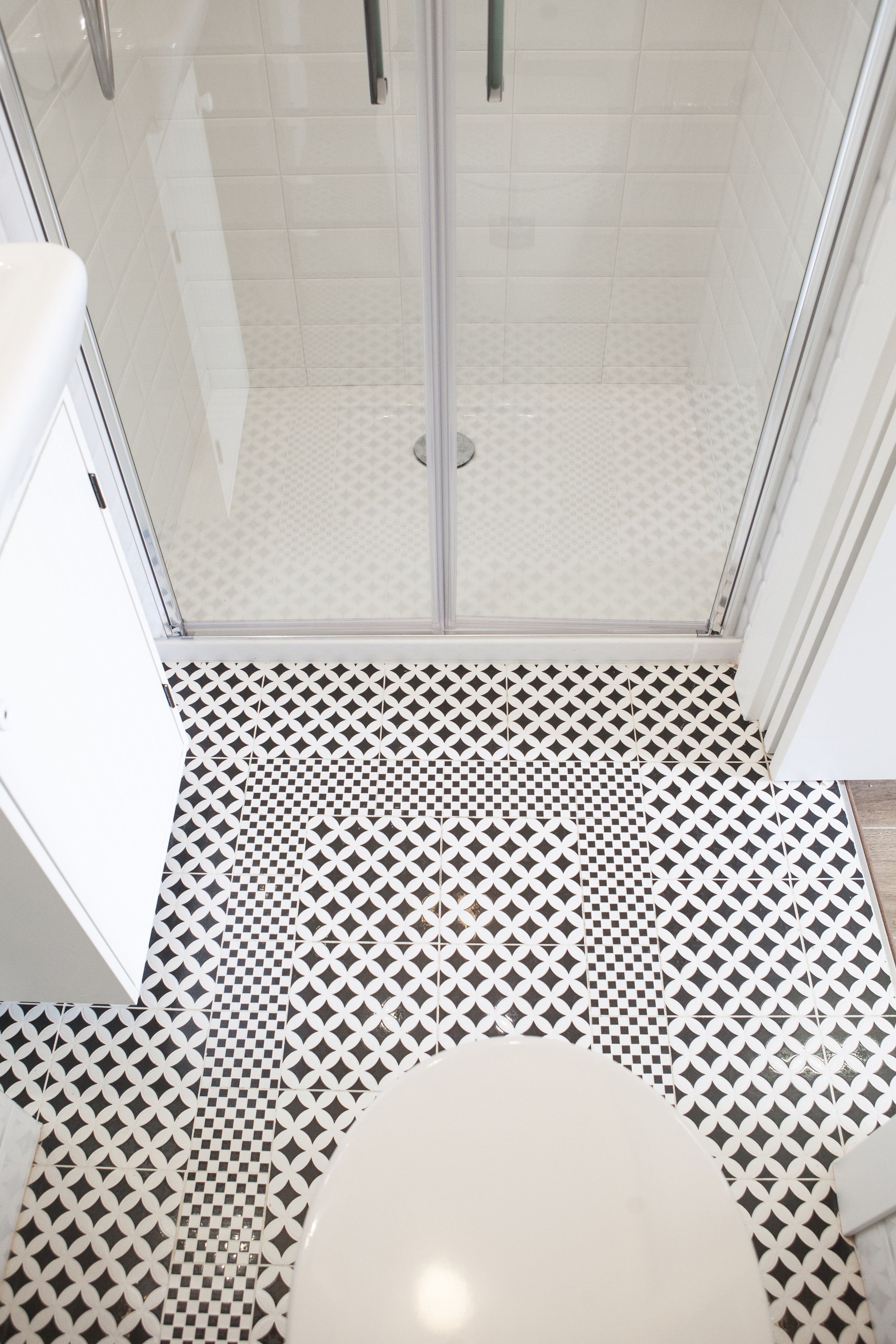A bathroom with a checkered floor pattern, a toilet, and a glass-enclosed shower area.