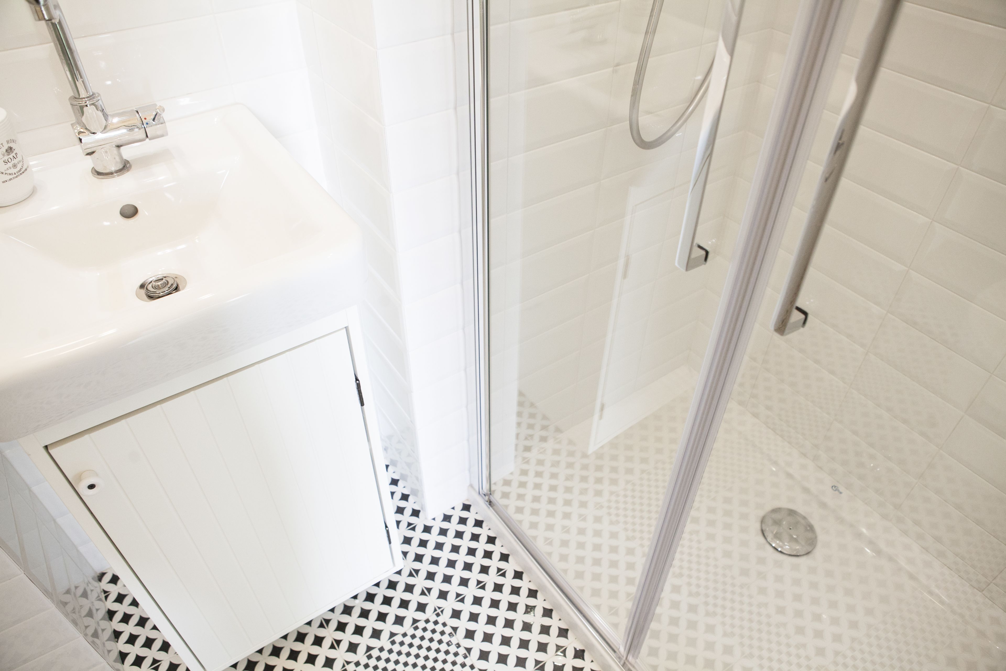 A bathroom with a white sink, a shower with a glass door, and a patterned floor.