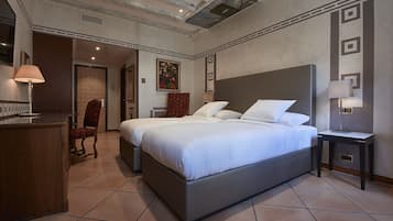 Una habitación de hotel con una cama grande, un escritorio, una silla y una pequeña mesa con lámpara.