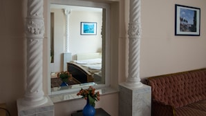 Una habitación con una cama, una ventana con vistas, un florero con flores y un cuadro en la pared.