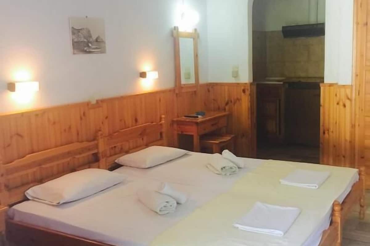 A double bed with two pillows and towels, wooden headboard, bedside table, and a mirror.