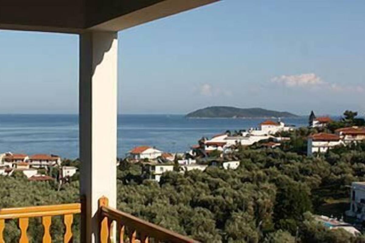 A balcony with a view of a coastal town, including houses and the sea.