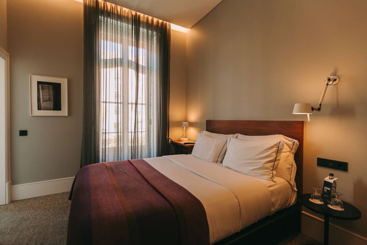 A neatly made bed with a headboard, a bedside table with a lamp, and a framed picture on the wall.