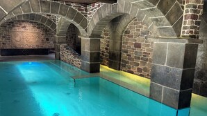 Una piscina interior con paredes de piedra y suelo de baldosas.