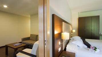 Ein Hotelzimmer mit Bett, Nachttisch, Lampe, Sessel und einer Couch.