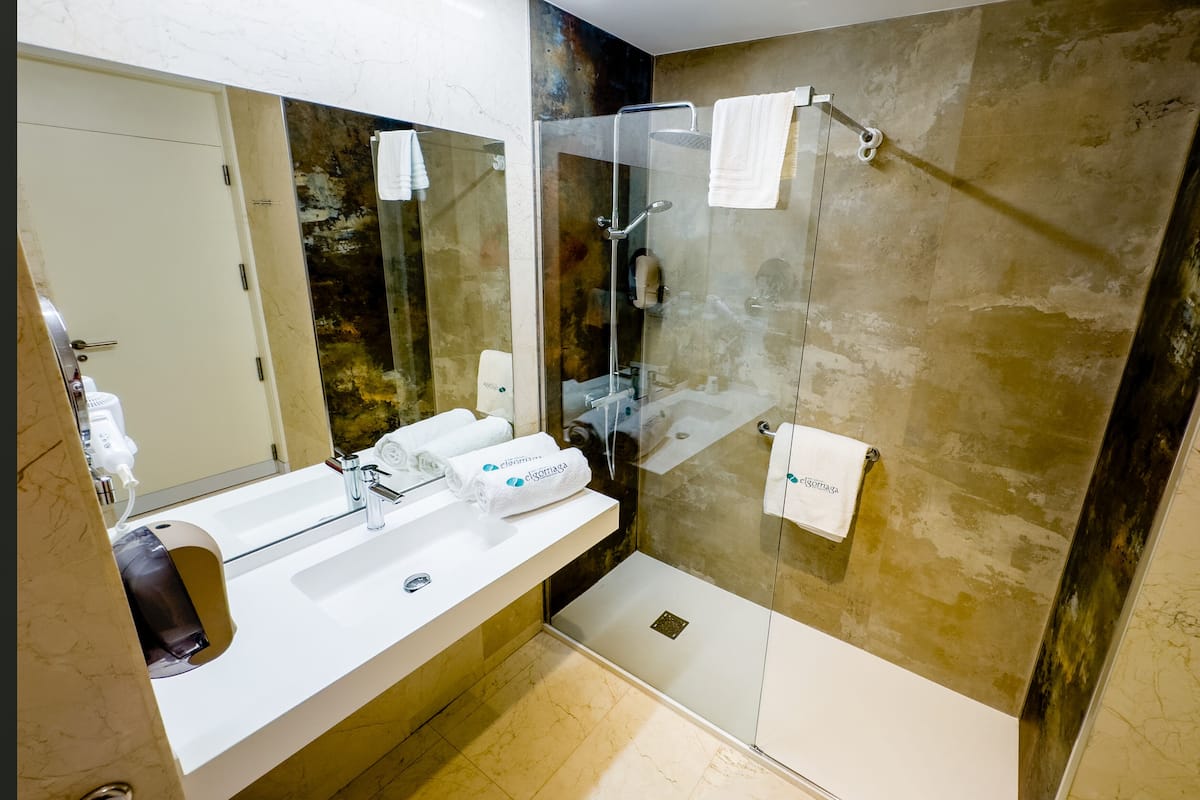 Un baño moderno con cabina de ducha de vidrio, un lavamanos blanco y un espejo grande.