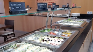 Un bufé con diversas opciones de comida, como ensaladas, platos de arroz y verduras mixtas.