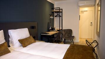 Een hotelkamer met een bed, bureau, stoel en een kapstok.