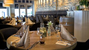 Un restaurante con mesas redondas dispuestas para comer, que incluye copas de vino, cubiertos y servilletas.