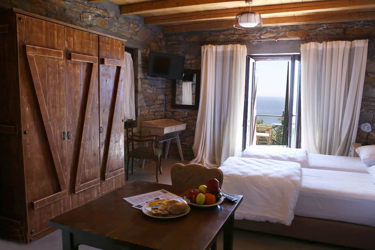 A room with a bed, a table with breakfast, a TV, and a stone wall.