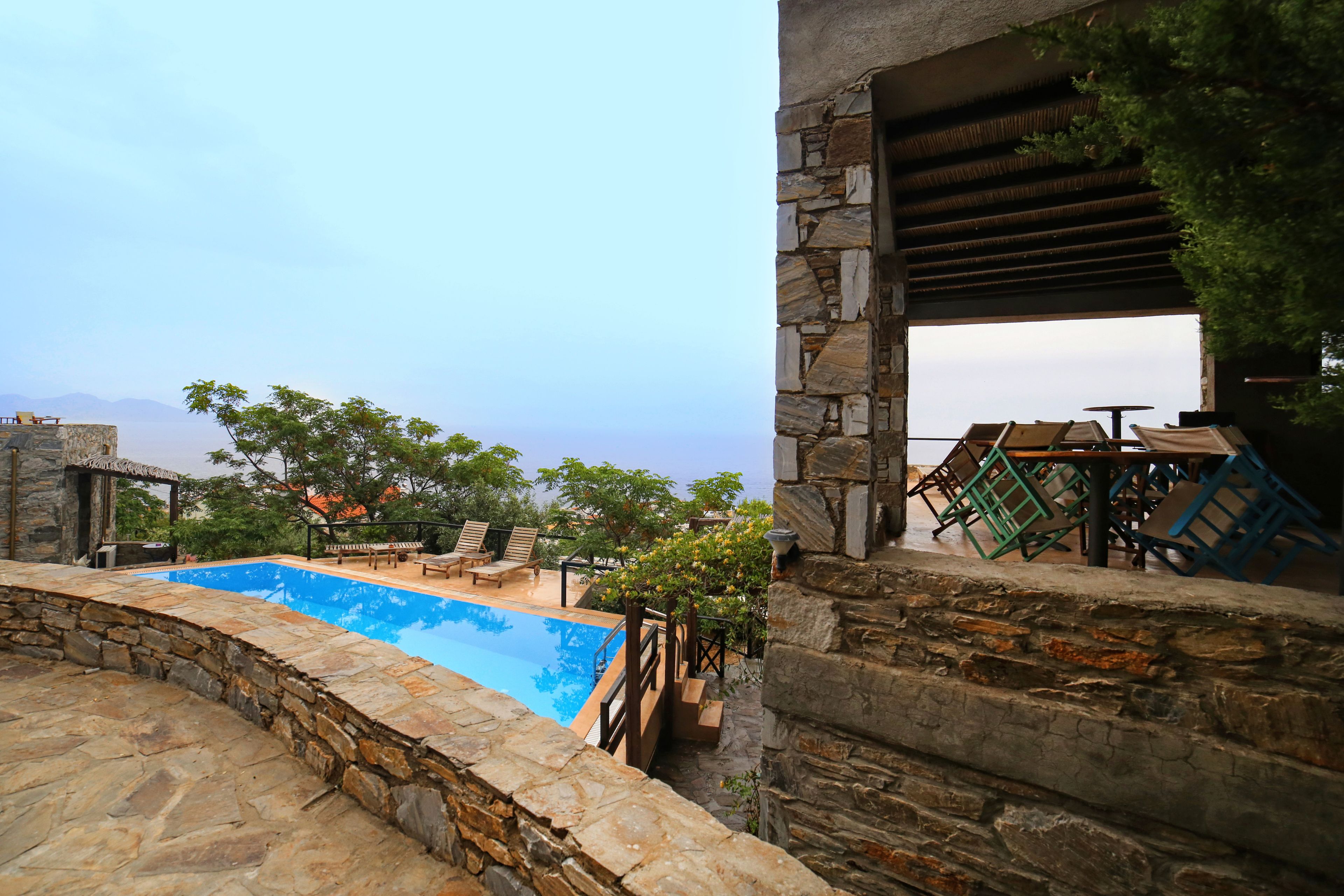 Una piscina de piedra con sillas de descanso y vistas a montañas.