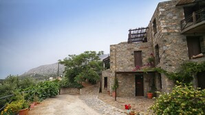 A stone building with a stone pathway leading to a wooden door. - Pyrgos Ikaria Traditional Village (Ikaria)