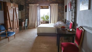 A bedroom with a bed, a desk, a chair, and a wardrobe. - Pyrgos Ikaria Traditional Village (Ikaria)