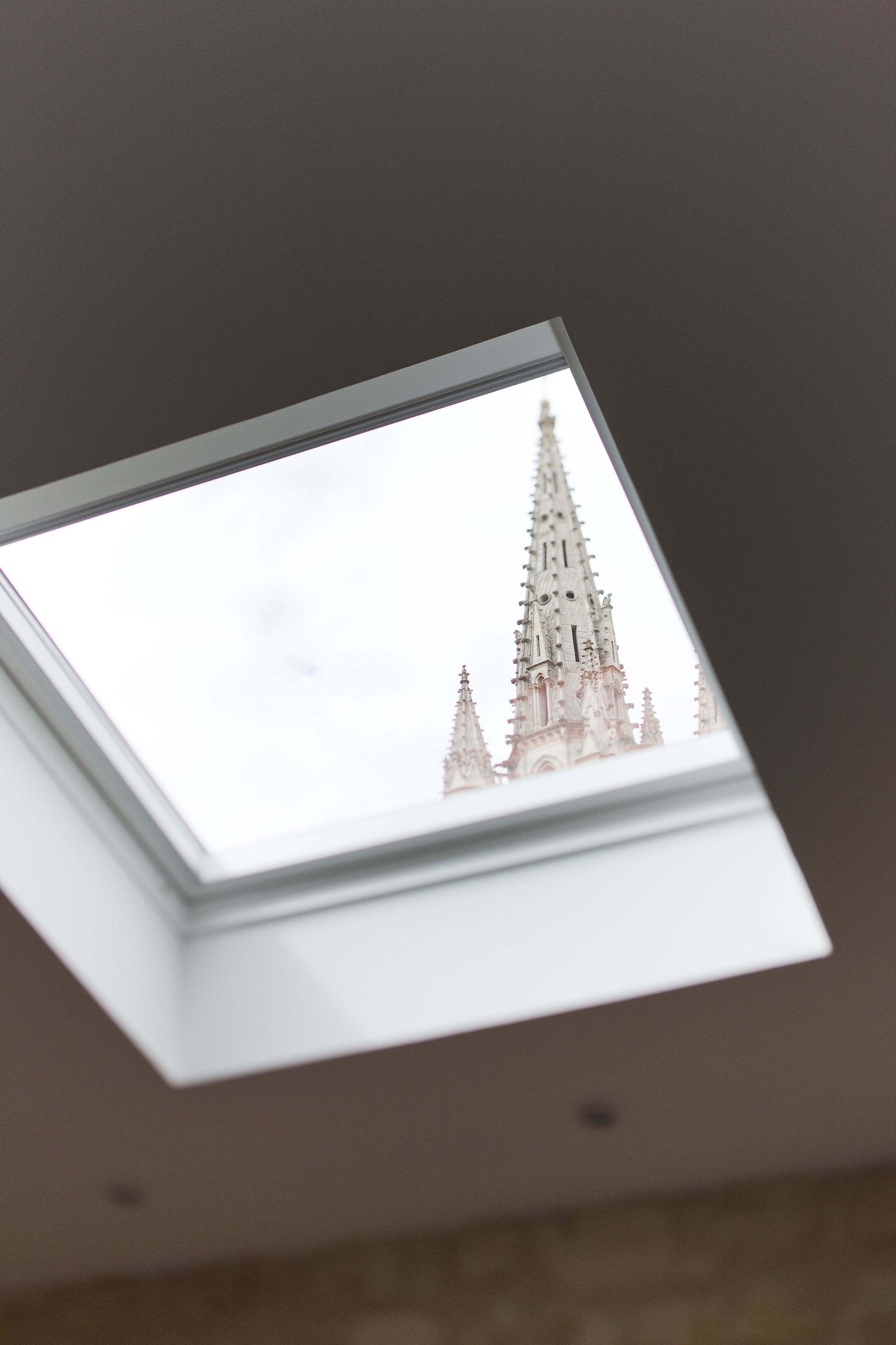 A skylight with a view of a tall, ornate church spire.