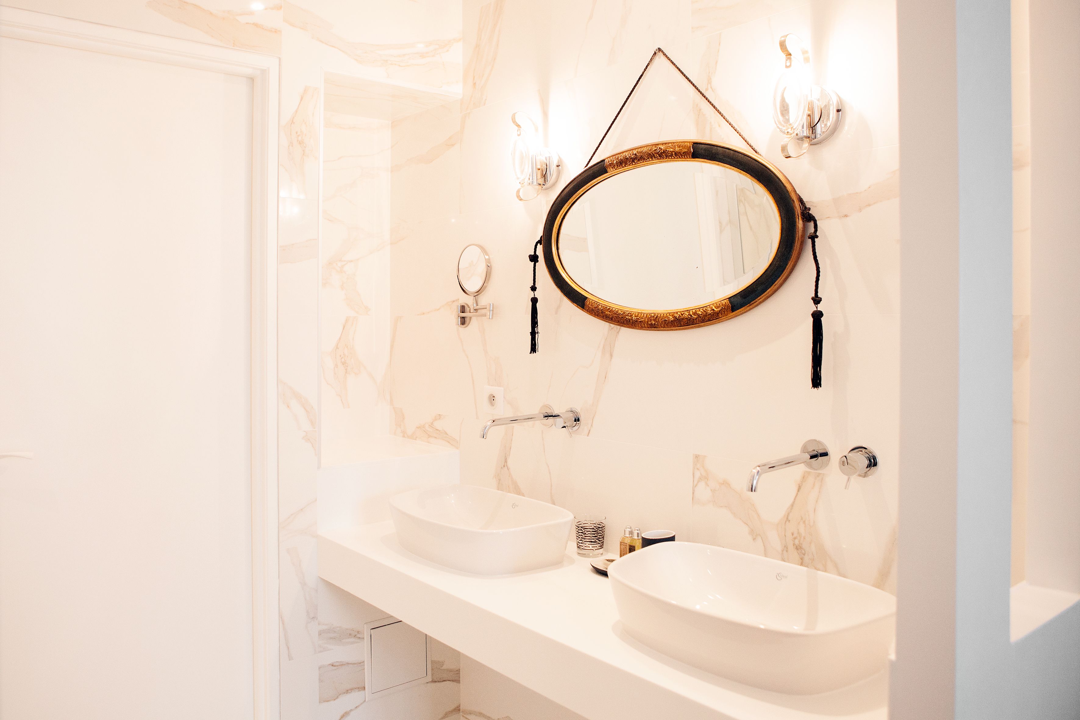 A bathroom with two sinks, a mirror, and a light fixture.