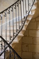 Primer plano de una escalera de piedra con barandillas de metal decoradas.