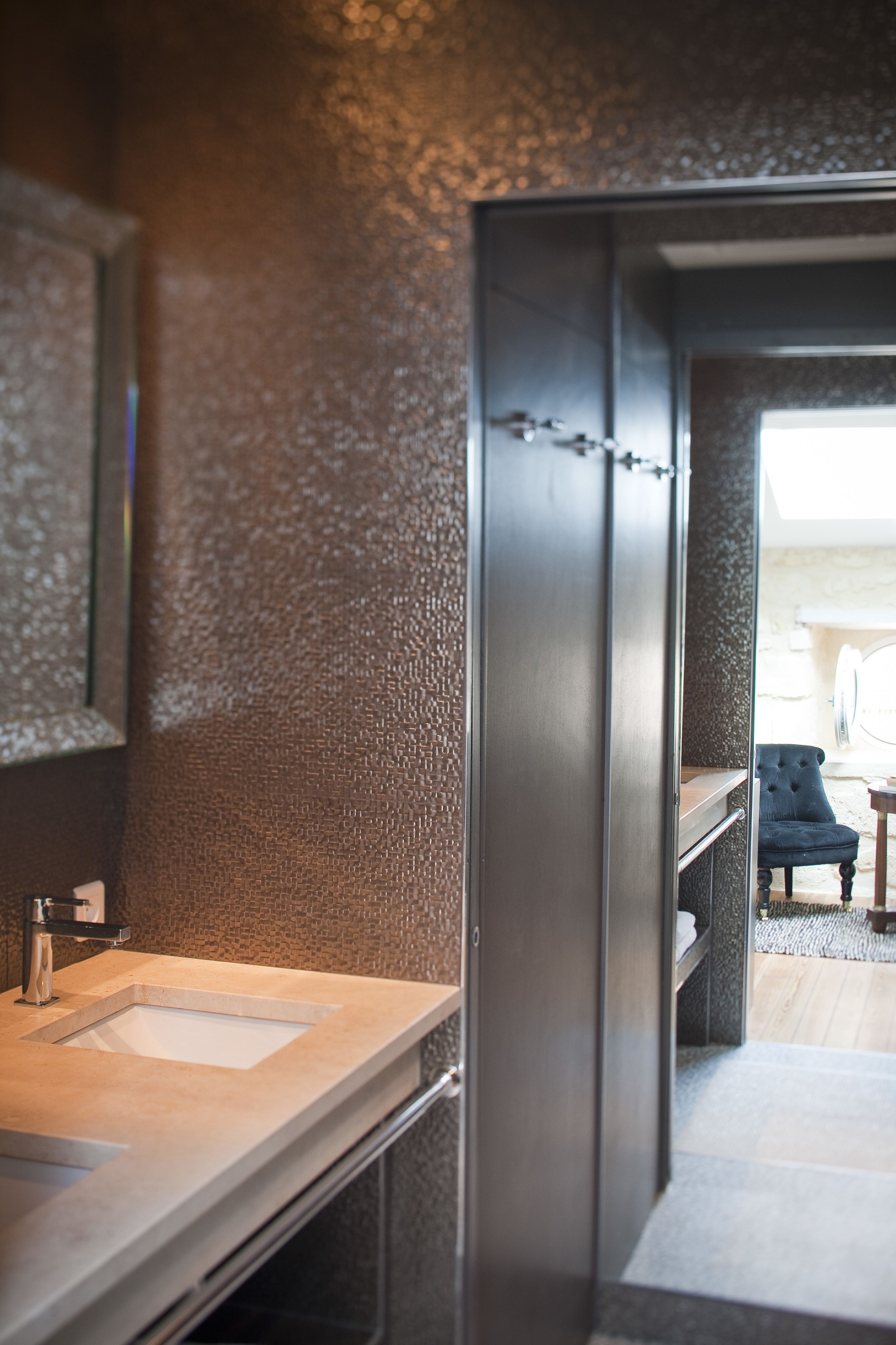 Un baño moderno con un espejo grande, un lavabo y un banco.