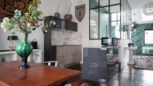 A modern kitchen with a marble countertop, a dining area with a wooden table, and a view of the living area through large windows. - Une Chambre chez Dupont (Bordeaux)