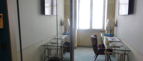 A conference room with glass tables, chairs, and two wall-mounted televisions.