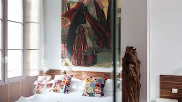 Ein Hotelzimmer mit einem großen Gemälde einer traditionellen Figur, einem hölzernen Kopfbrett und einer dekorativen Holzskulptur.