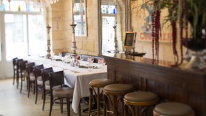 A restaurant with a long table set for dining, wooden chairs, and a bar area with stools. - Une Chambre chez Dupont (Bordeaux)